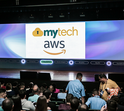 Telão apresentando mytech e aws em um auditório.
